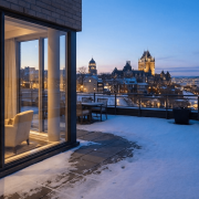 Vue panoramique depuis la terrasse enneigée d'une propriété de prestige surplombant le Château Frontenac et le Vieux-Québec au crépuscule.
