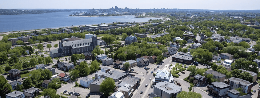 Vue d'une rue résidentielle bordée d'arbres et de maisons ancestrales dans le quartier Vieux-Bourg Beauport à Québec.